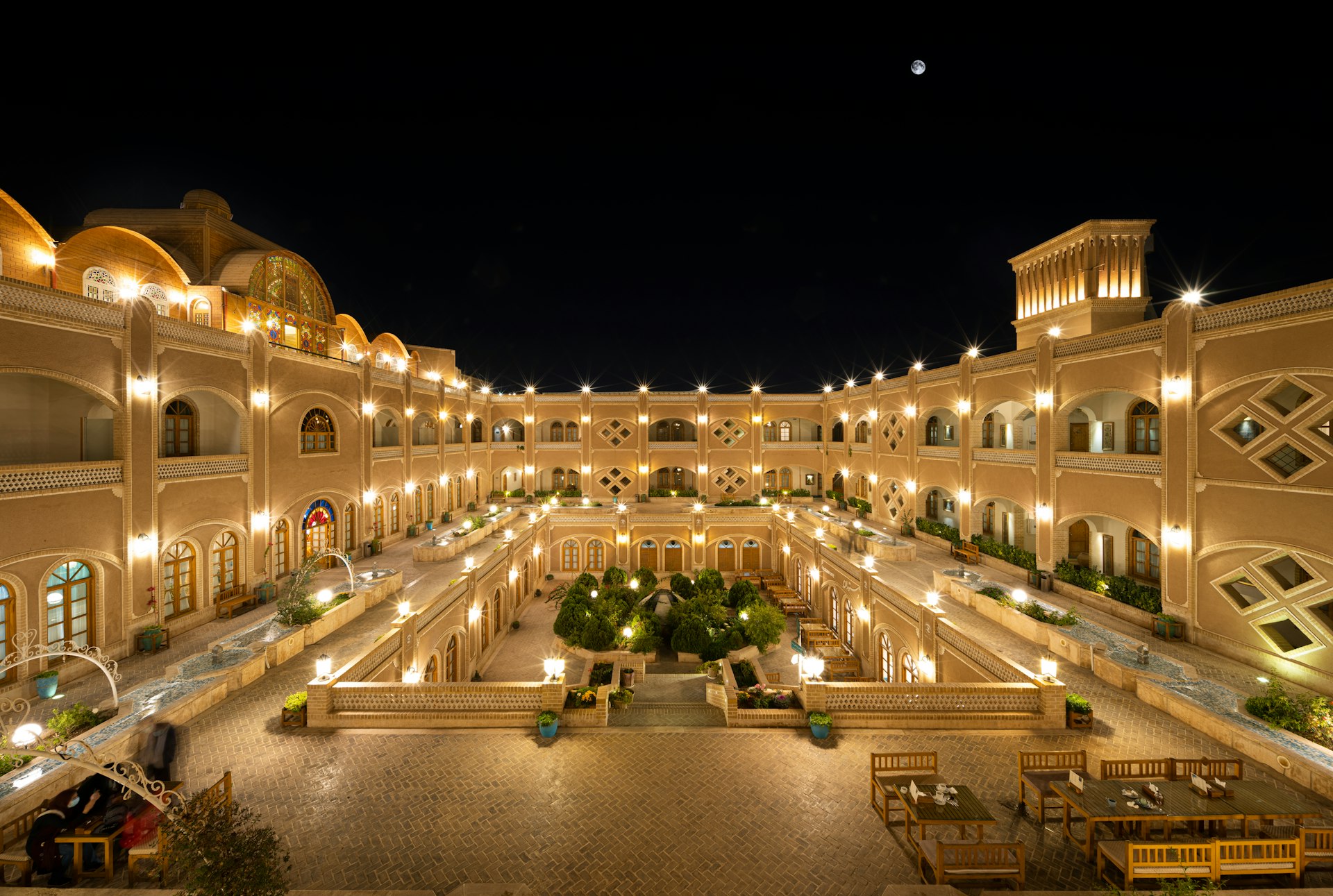 a large building with many windows and a courtyard with tables and chairs