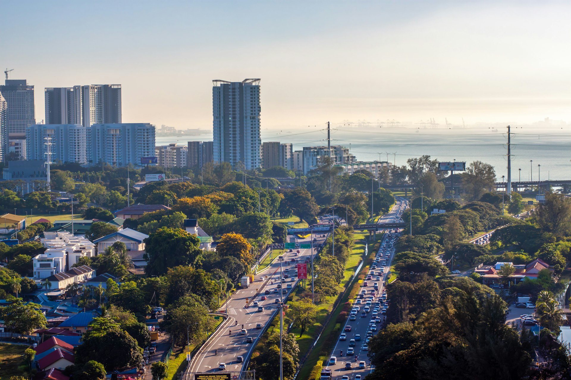Cityscape with buildings, highway, and a sea view.