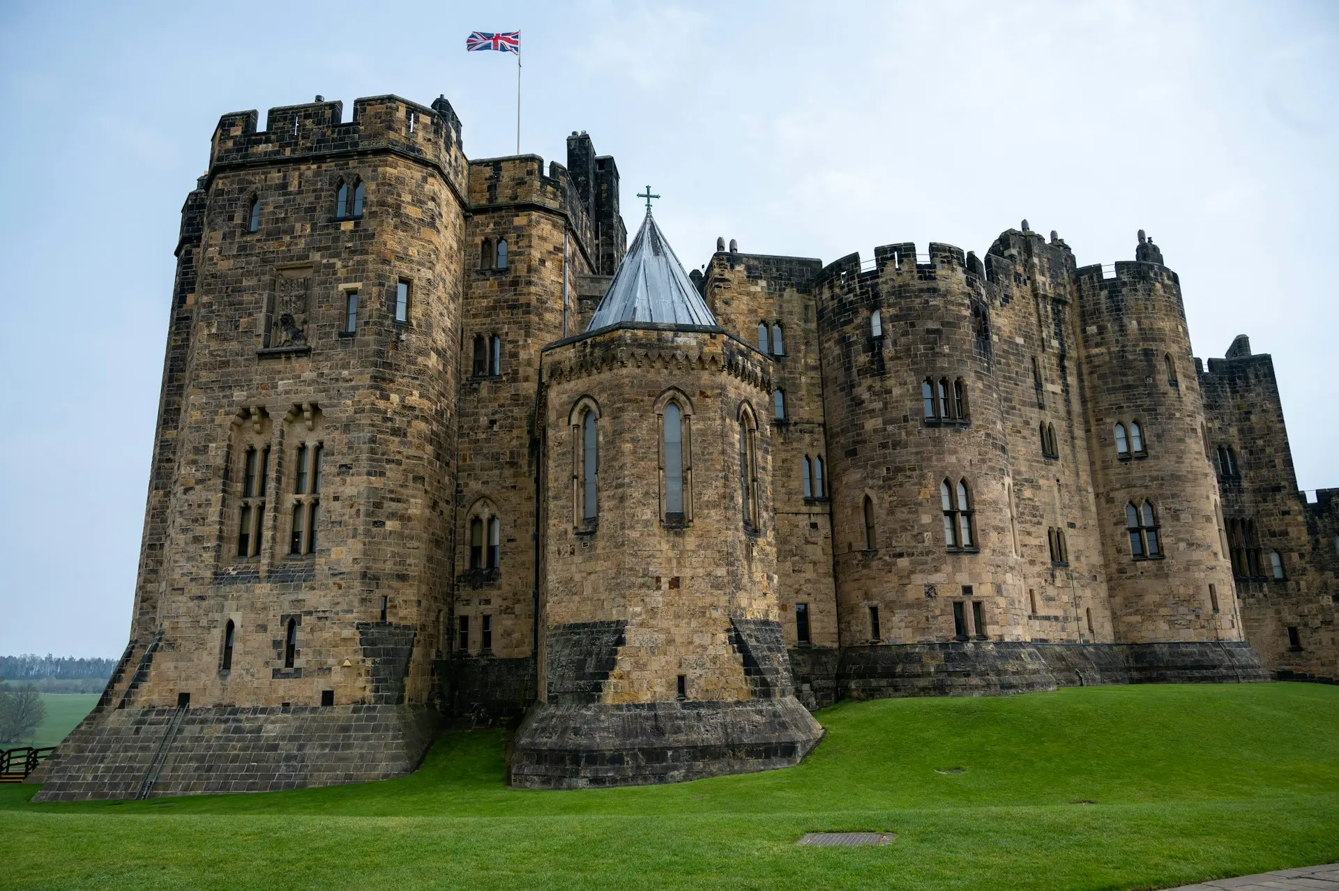 a castle with a flag on top with Alnwick Castle in the background