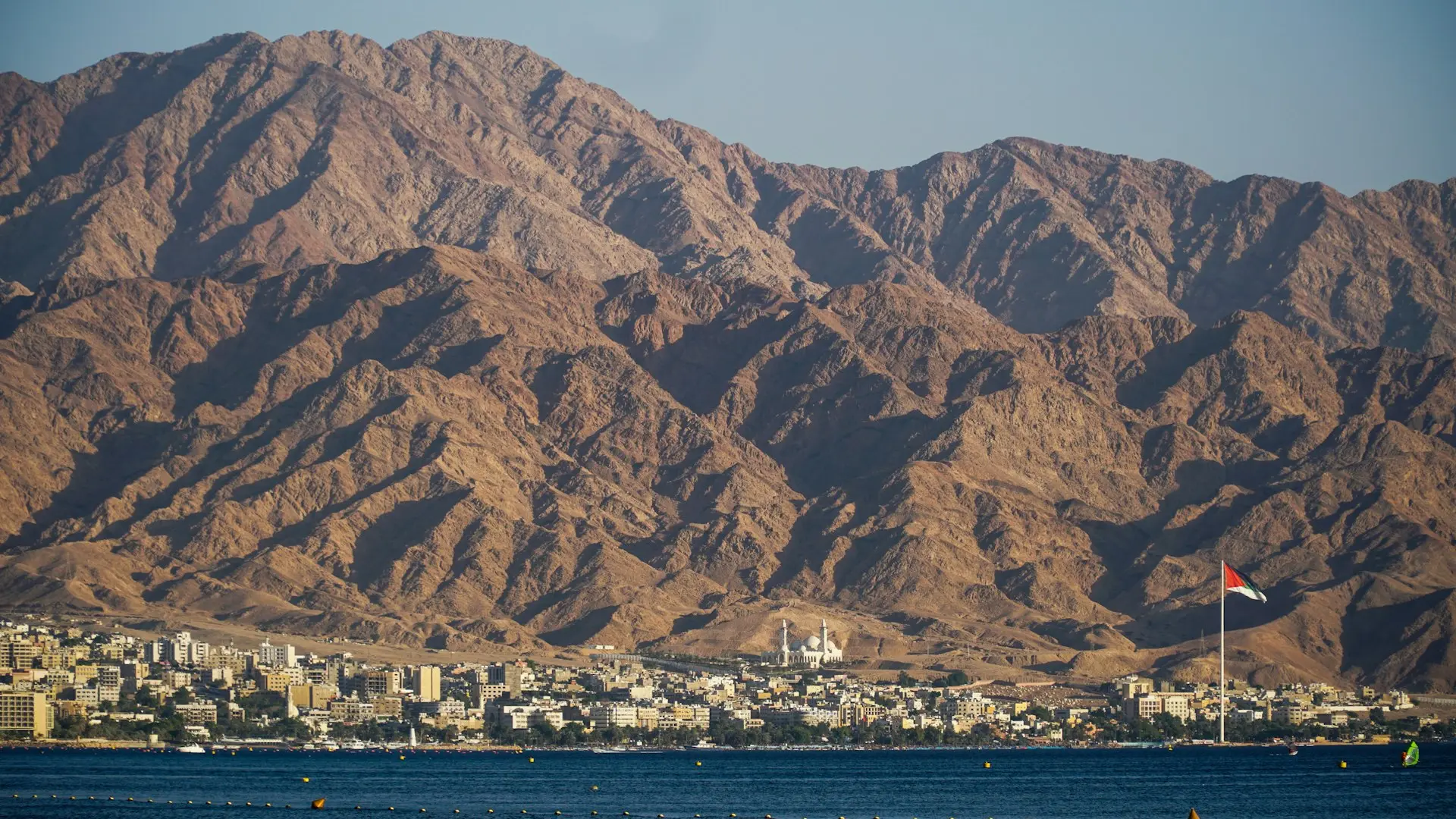 brown mountain near body of water during daytime