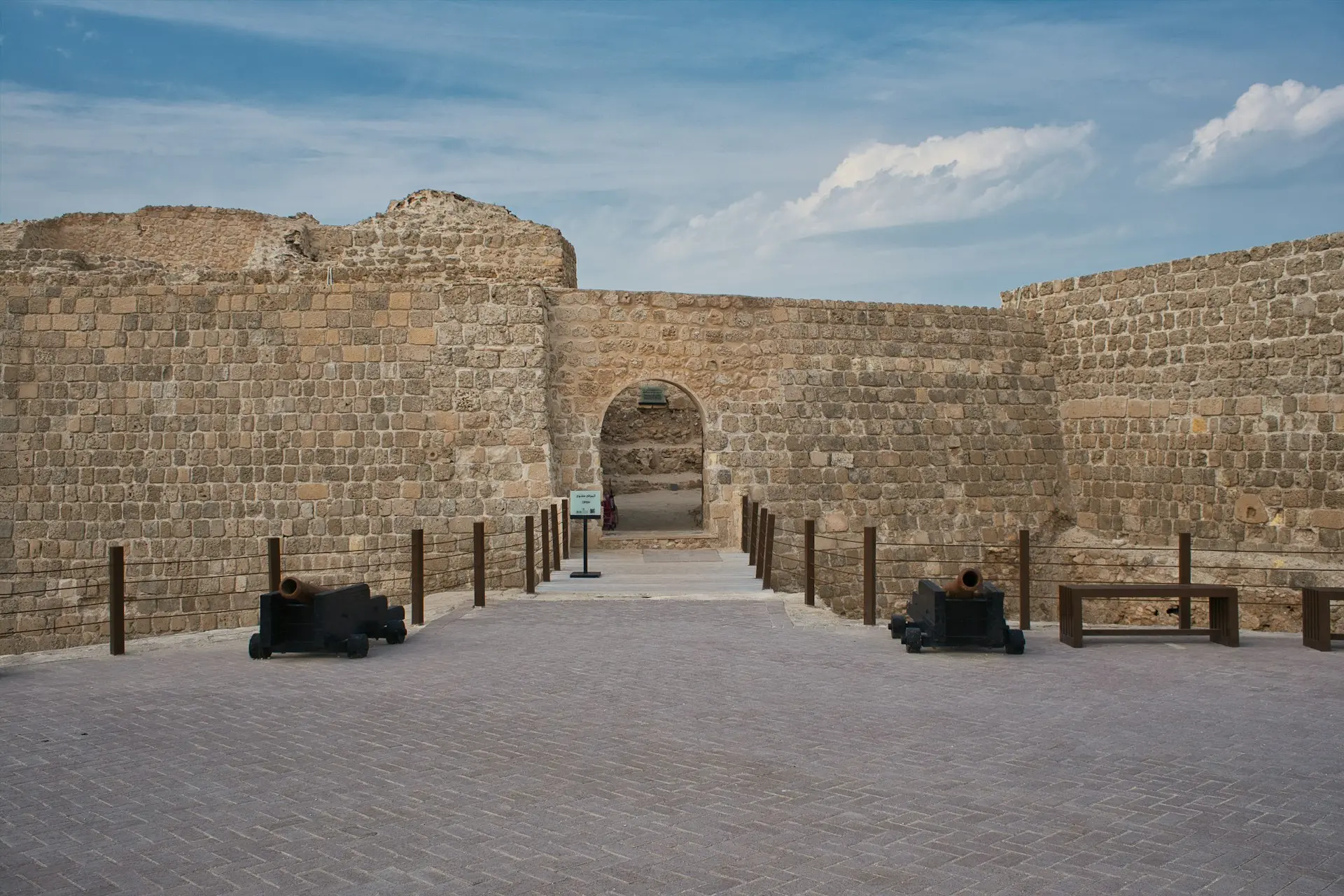 two people sitting on a bench in front of a stone wall