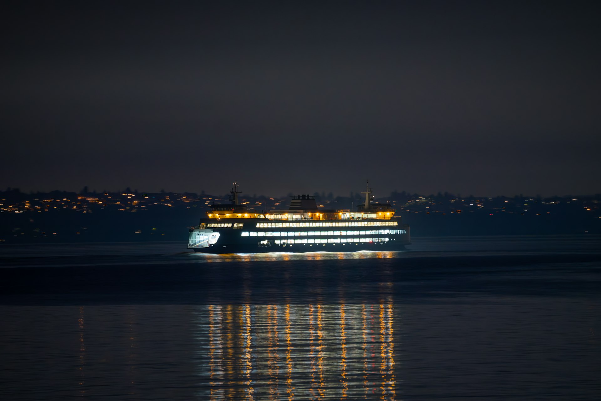 A ferry sails across water at night.