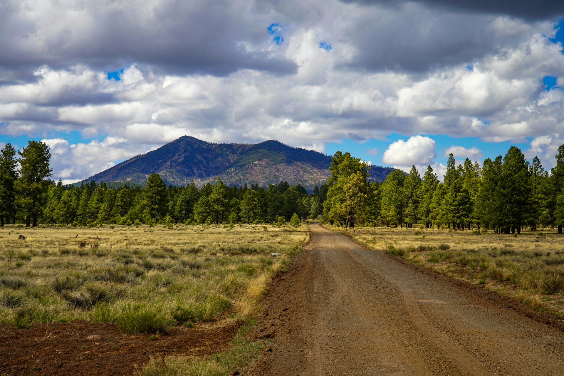 A dirt road leads to a mountain beneath clouds.