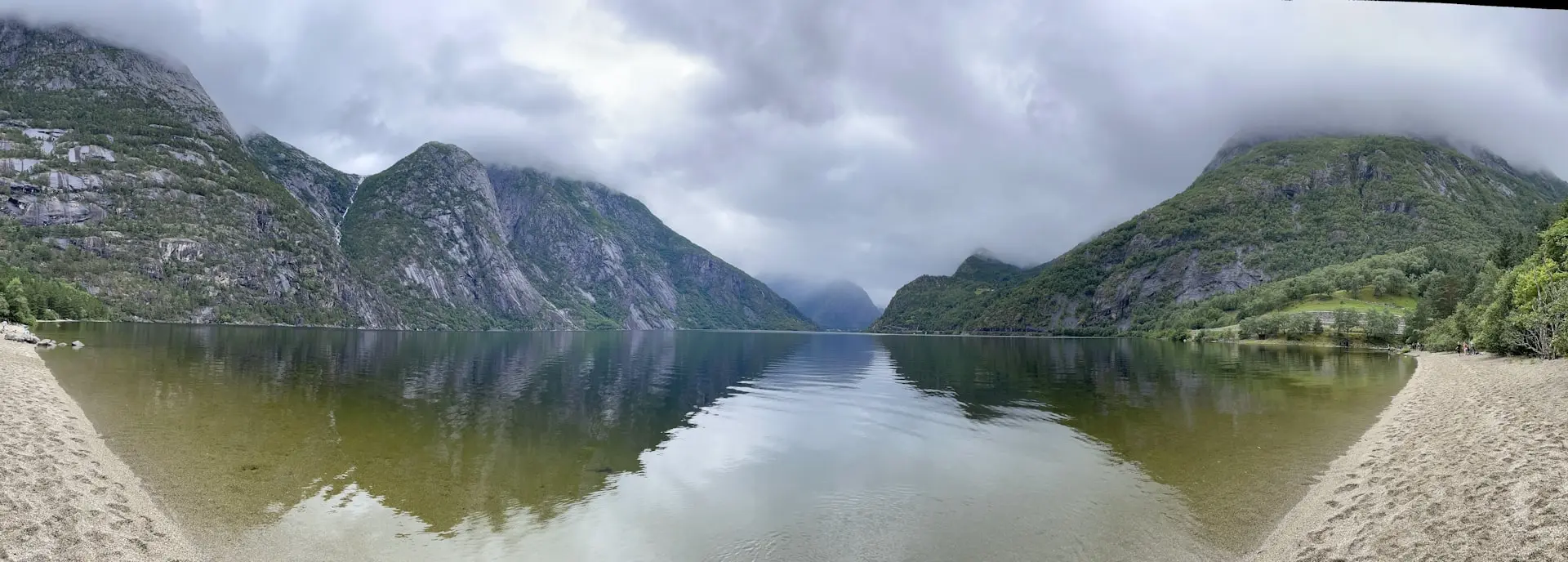 a body of water surrounded by mountains under a cloudy sky