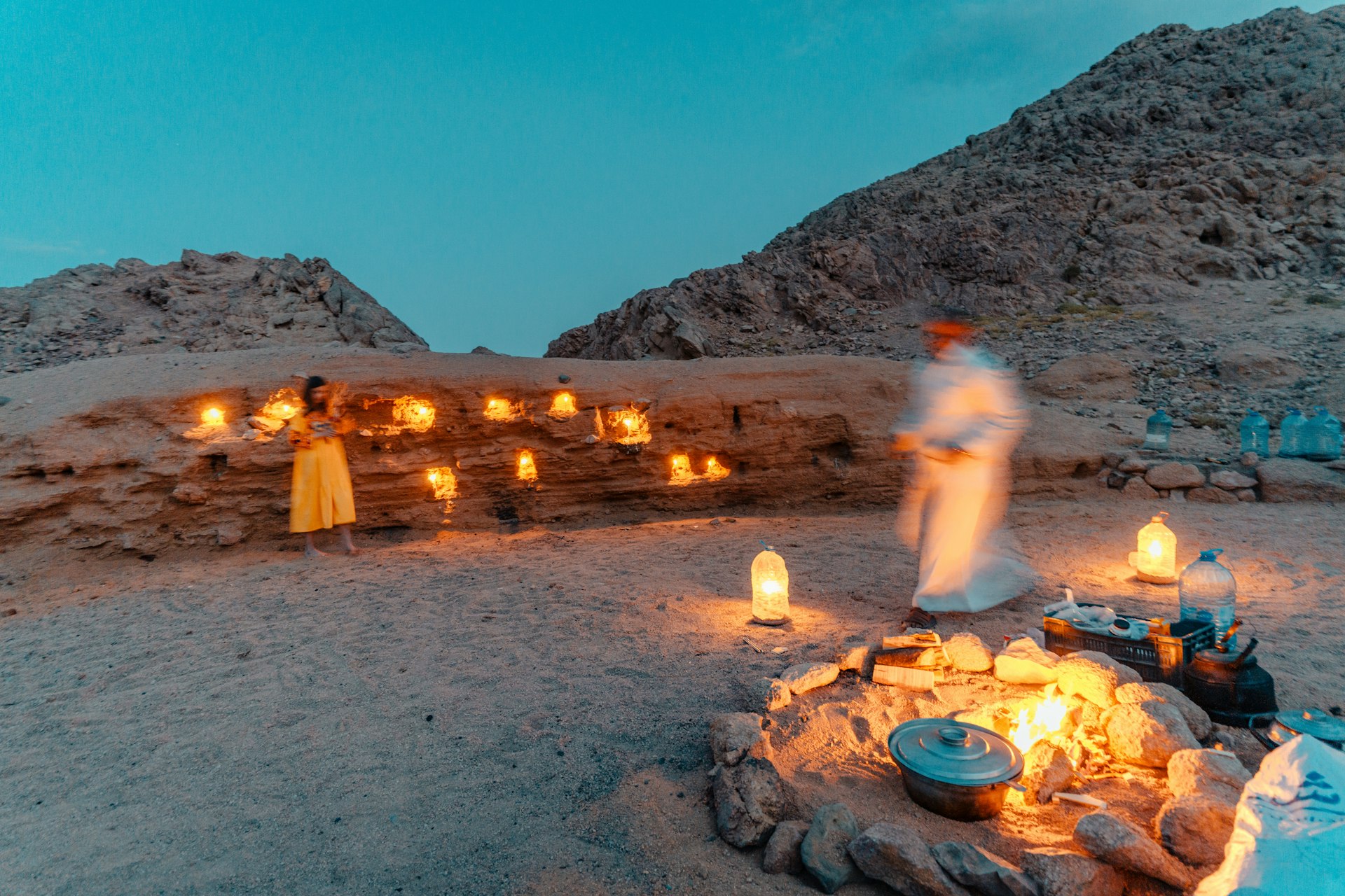 a group of people around a fire pit with a group of candles